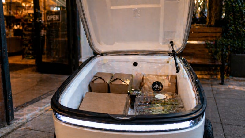 Inside the robot's insulated cargo compartment: takeout containers and grocery items collected from a vendor, ready for delivery to a student on campus